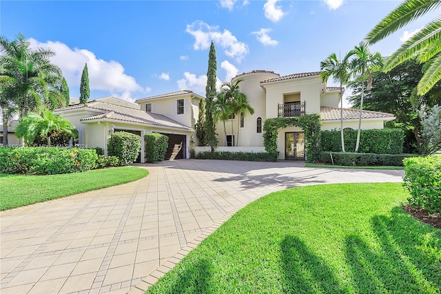 mediterranean / spanish house with a balcony, a garage, and a front lawn