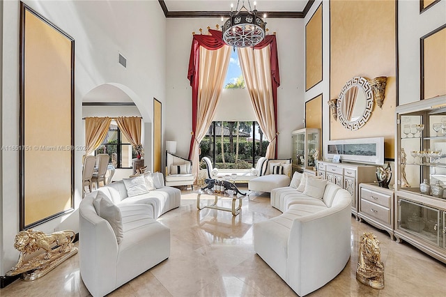 living room featuring a towering ceiling, a chandelier, and crown molding