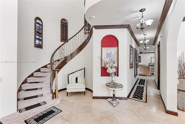 foyer with an inviting chandelier, a textured ceiling, light tile patterned floors, and crown molding