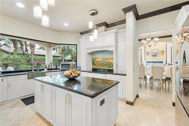 kitchen with white cabinets, hanging light fixtures, sink, a center island, and a notable chandelier