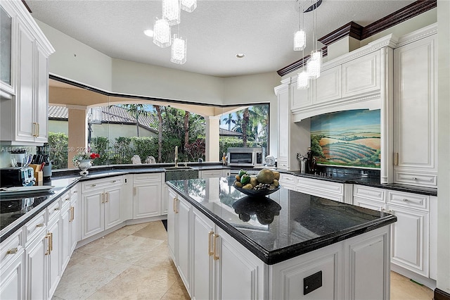 kitchen with a notable chandelier, white cabinets, plenty of natural light, and a kitchen island