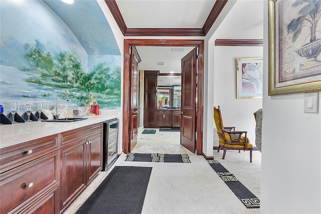 interior space featuring ornamental molding, beverage cooler, sink, and light colored carpet