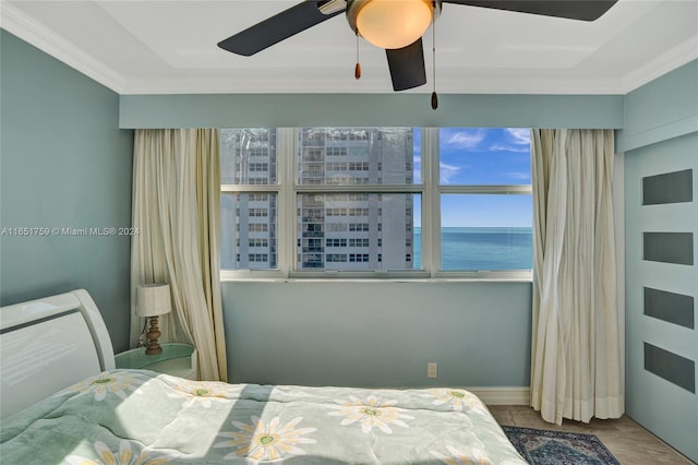 bedroom with ornamental molding, a water view, and ceiling fan