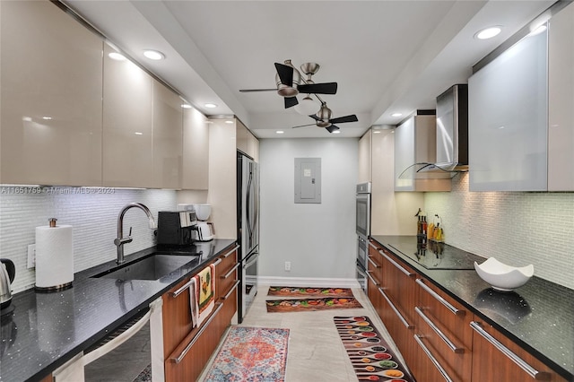 kitchen with wall chimney range hood, stainless steel appliances, dark stone counters, and sink