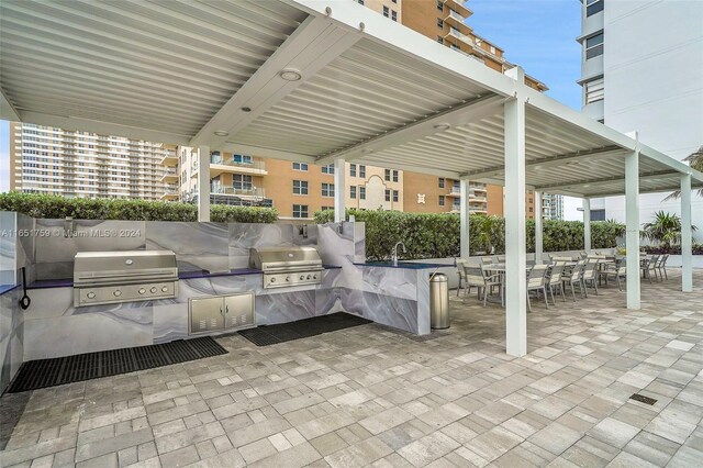 view of patio featuring a balcony, area for grilling, sink, and a grill