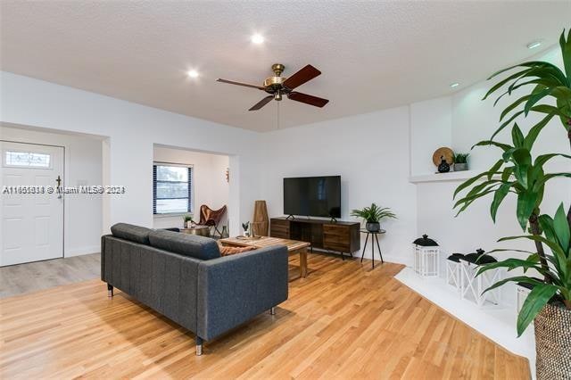 living room with ceiling fan, a textured ceiling, and light hardwood / wood-style flooring