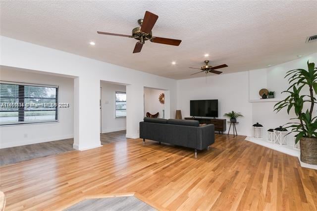 living room featuring a textured ceiling, light hardwood / wood-style flooring, and ceiling fan