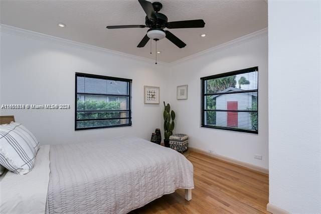 bedroom featuring ceiling fan, wood-type flooring, and ornamental molding