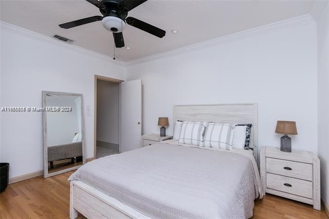 bedroom featuring crown molding, light hardwood / wood-style flooring, and ceiling fan