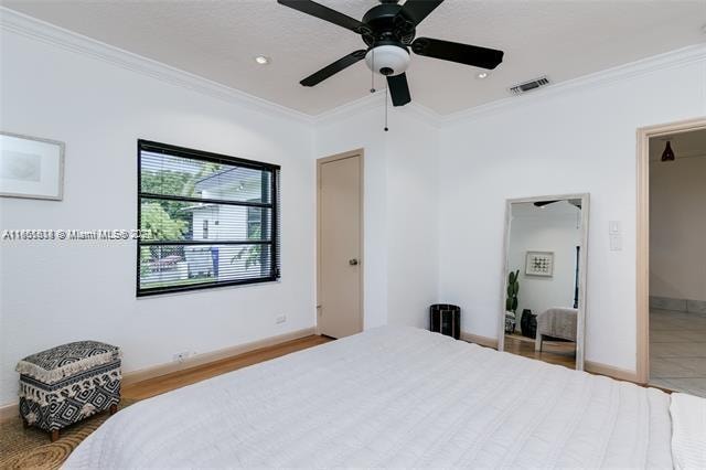 bedroom with crown molding, hardwood / wood-style floors, and ceiling fan