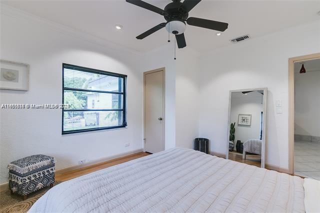 bedroom with ceiling fan, wood-type flooring, and ornamental molding