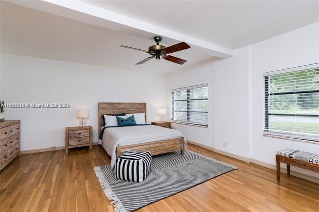 bedroom with ceiling fan, beamed ceiling, and hardwood / wood-style floors