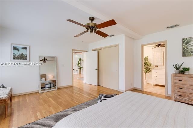 bedroom with a closet, beam ceiling, light hardwood / wood-style floors, connected bathroom, and ceiling fan