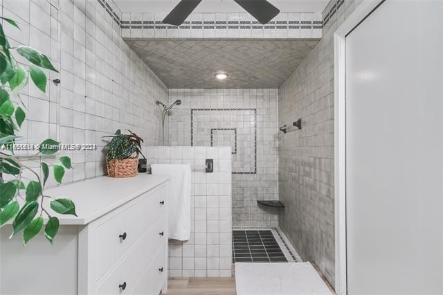 bathroom with vanity, ceiling fan, and a tile shower