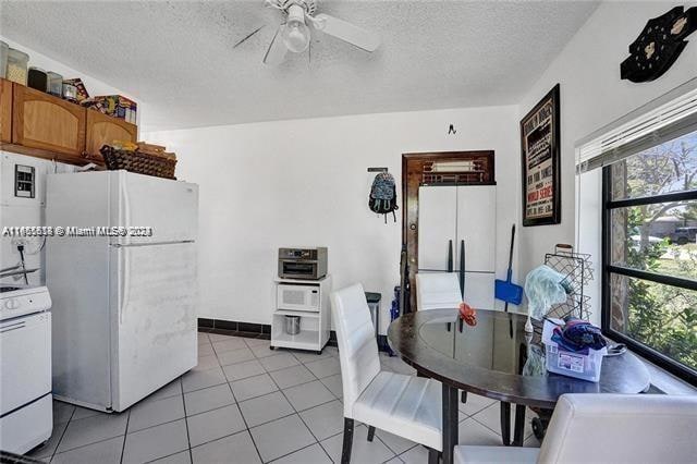 tiled dining space with a textured ceiling, a healthy amount of sunlight, and ceiling fan