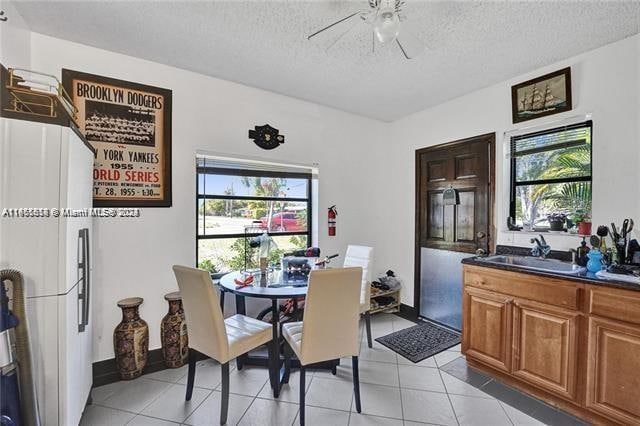 tiled dining area with a textured ceiling, ceiling fan, and sink