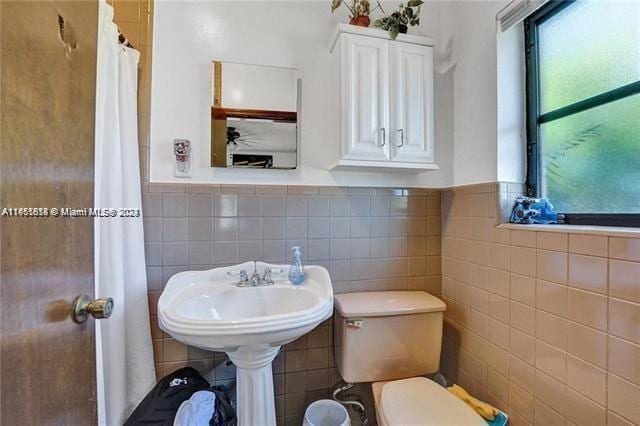 bathroom with tile walls and toilet