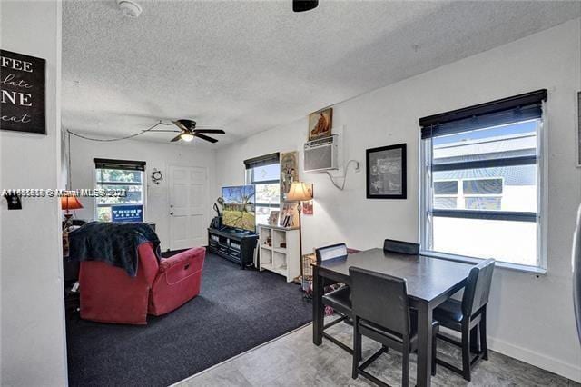 home office with ceiling fan, plenty of natural light, a wall mounted air conditioner, and a textured ceiling