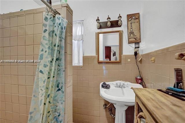 bathroom with tile walls and a shower with shower curtain