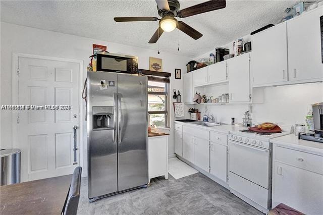 kitchen featuring white range oven, stainless steel fridge, white cabinetry, and ceiling fan