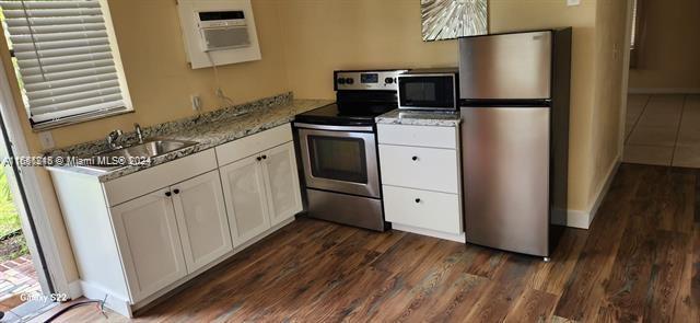 kitchen featuring dark wood-type flooring, sink, stainless steel appliances, and white cabinets