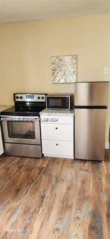 kitchen with wood-type flooring, stainless steel appliances, and white cabinetry