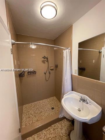 bathroom with tile walls, a shower with curtain, and sink