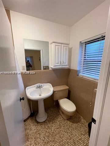 bathroom with tile walls, toilet, and tile patterned floors