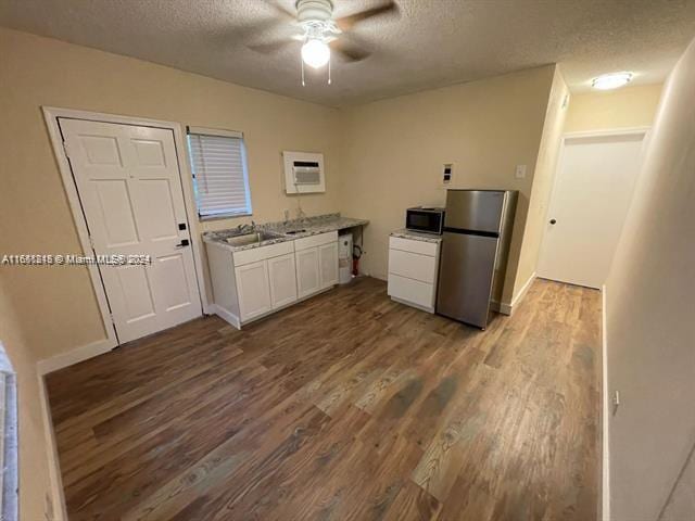 kitchen featuring a textured ceiling, hardwood / wood-style floors, appliances with stainless steel finishes, ceiling fan, and white cabinets