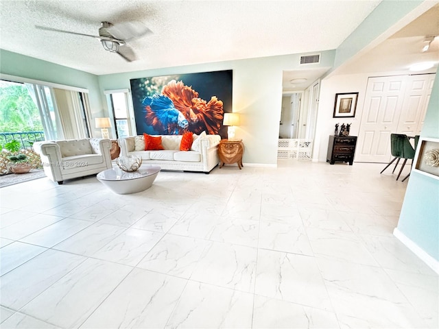 living room featuring ceiling fan and a textured ceiling