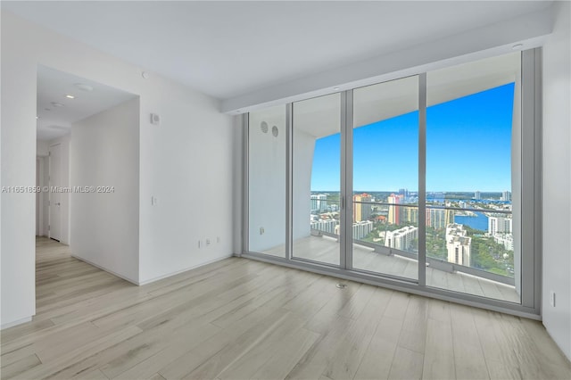 empty room featuring light hardwood / wood-style flooring, a water view, and expansive windows