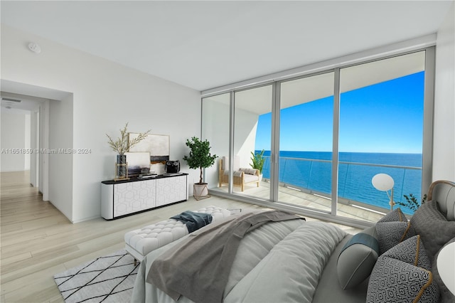 bedroom featuring light hardwood / wood-style flooring, floor to ceiling windows, and a water view