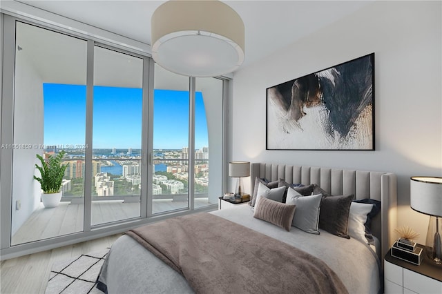 bedroom featuring wood-type flooring, a wall of windows, and a water view