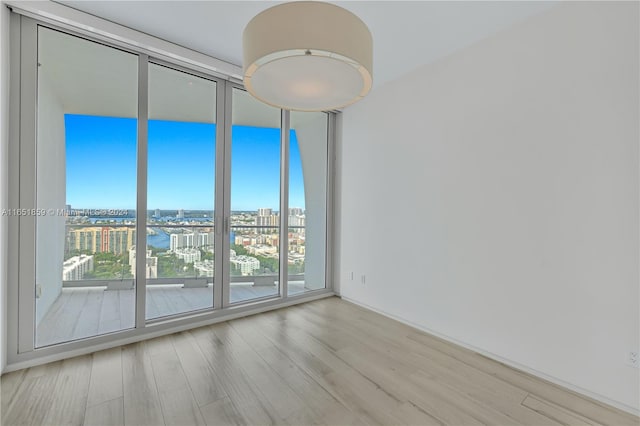 unfurnished room with a wall of windows and light wood-type flooring