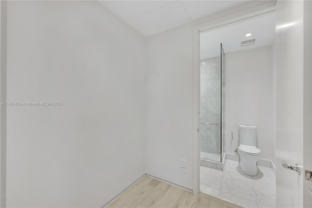 bathroom featuring walk in shower, hardwood / wood-style floors, and toilet