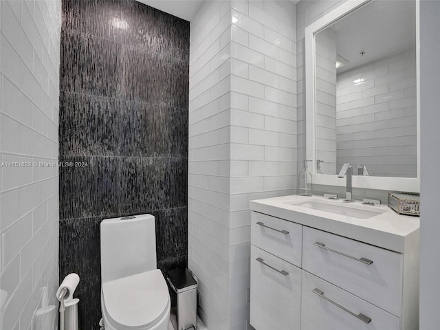 bathroom featuring vanity, toilet, and tile walls