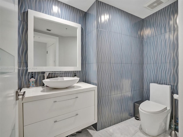 bathroom with vanity, toilet, and tile walls