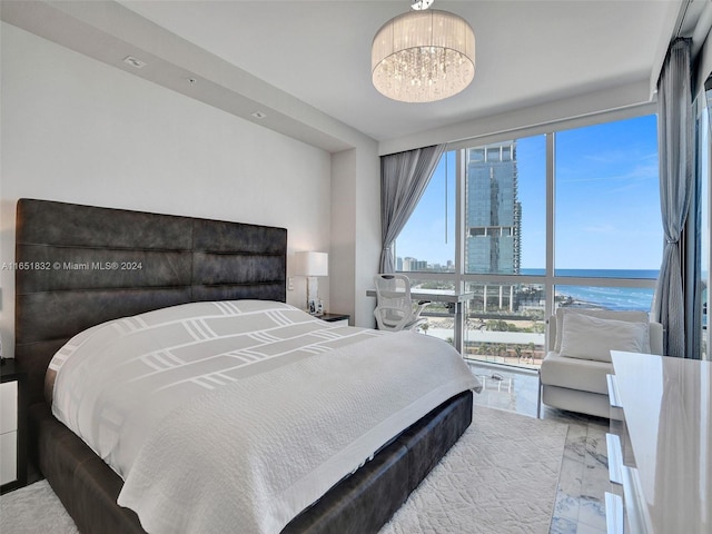 bedroom featuring multiple windows, a water view, expansive windows, and an inviting chandelier