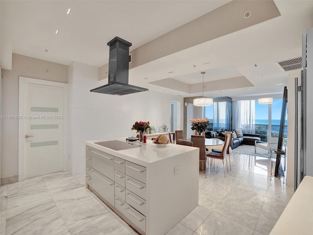 kitchen with a water view, a raised ceiling, a kitchen island, island exhaust hood, and black electric cooktop