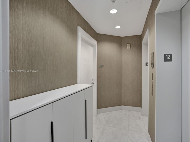 hallway featuring elevator and light tile patterned floors