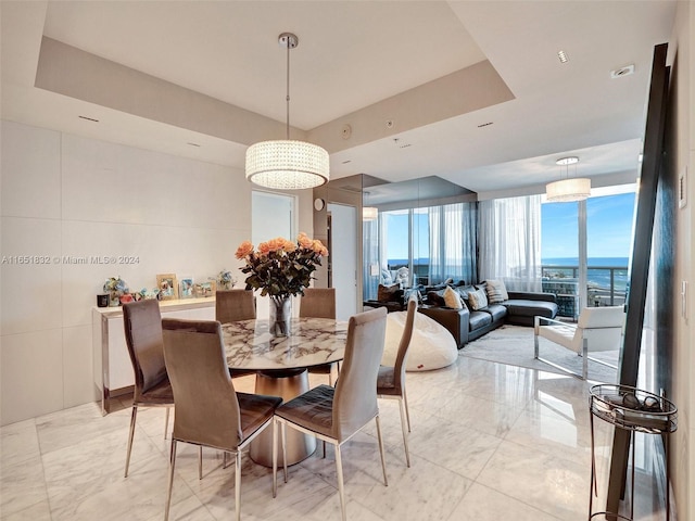 dining space featuring a water view, floor to ceiling windows, and a tray ceiling