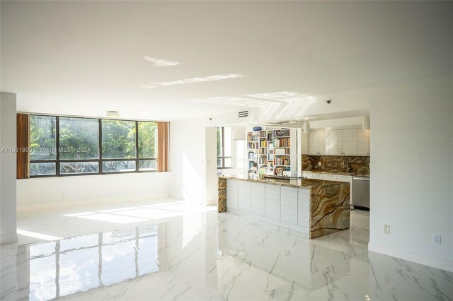 kitchen featuring dishwasher, a kitchen island with sink, decorative backsplash, white cabinetry, and light stone counters