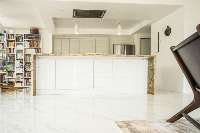 interior space with stainless steel fridge and light stone countertops