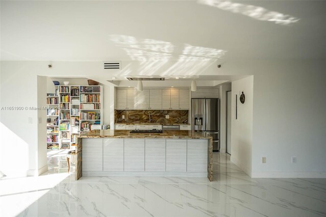 kitchen with dark stone countertops, stainless steel fridge, and decorative backsplash