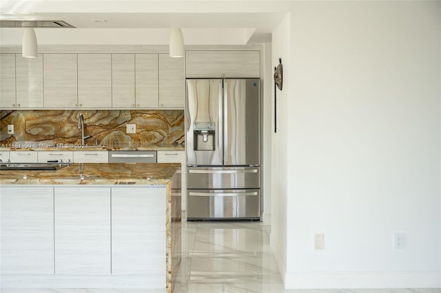 kitchen with backsplash, light stone counters, sink, and appliances with stainless steel finishes