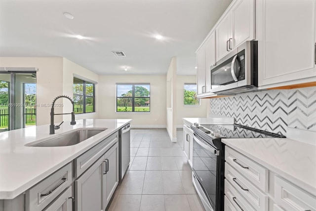 8123 NW 78th St, Tamarac, FL 33321 - kitchen with stainless steel appliances, light countertops, backsplash, light tile patterned floors, and an island with sink