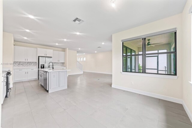8123 NW 78th St, Tamarac, FL 33321 - kitchen with light countertops, open floor plan, decorative backsplash, white cabinets, and an island with sink