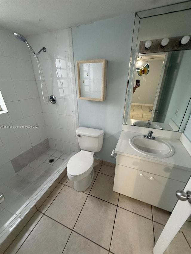 bathroom with vanity, tile patterned flooring, a tile shower, and toilet