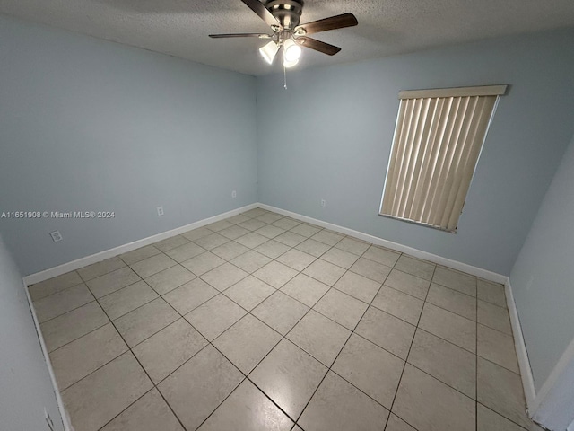 tiled spare room featuring a textured ceiling and ceiling fan