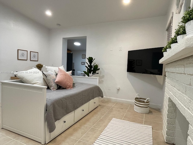 bedroom with light tile patterned flooring and a stone fireplace